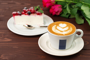 Cup of latte coffee with piece of berry cheesecake