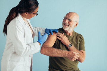 Doctor giving vaccination to elderly man - obrazy, fototapety, plakaty