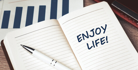 The words Enjoy Life written on a white notebook. Work and study concept