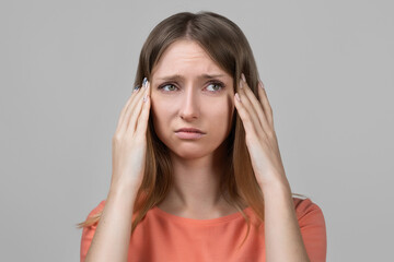 Concerned, frustrated young blond girl feeling fatigue, as suffer pain in head, painful headache or migraine