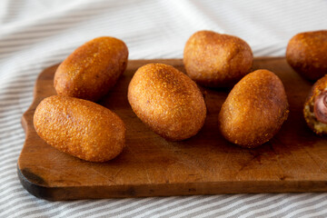 Homemade Mini Corn Dogs on a rustic wooden board, side view. Close-up.