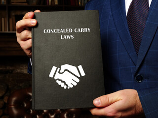  CONCEALED CARRY LAWS book in the hands of a lawyer. Concealed carry is legal in most jurisdictions of the United States