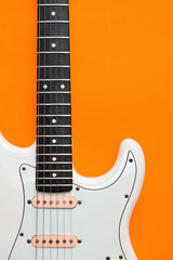 Obraz premium Detail of White Electric Guitar on a orange background.