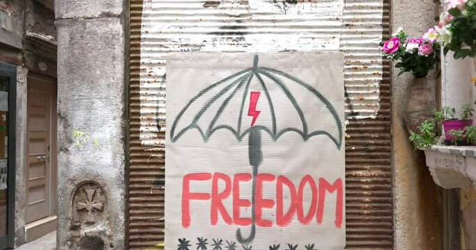 Lightning symbol in umbrella and strajk kobiet in polish text translation strike protest of women against forced abortion on a poster on a wall in narrow passage Venice Italy
