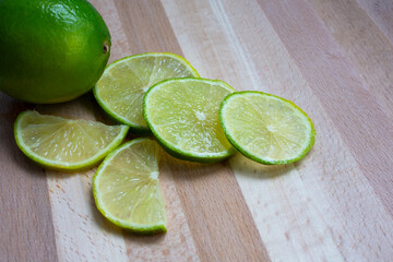 Juicy ripe citrus on an old wooden table - lime green whole and in round slices