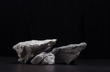 Rough natural grey stone as podium for packaging and cosmetic presentation on black background,...
