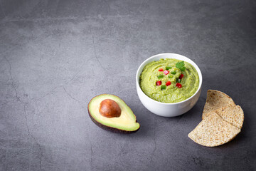 Bowl of guacamole and nachos isolated on dark background.