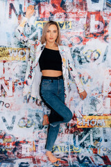 fashionable woman with graffitti style background coloured blazer jacket business crazy style blue jeans black top sexy