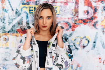 Fototapeta premium fashionable woman with graffitti style background coloured blazer jacket business crazy style blue jeans black top sexy