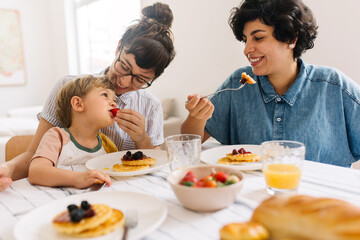 Obraz na płótnie Canvas Casal lésbicas comendo café da manhã com filho em casa 