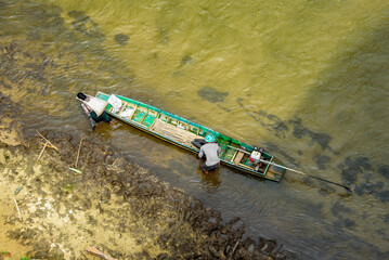 View from above, a villager having sacksful of goods strapped to her forehead as she leaves the...