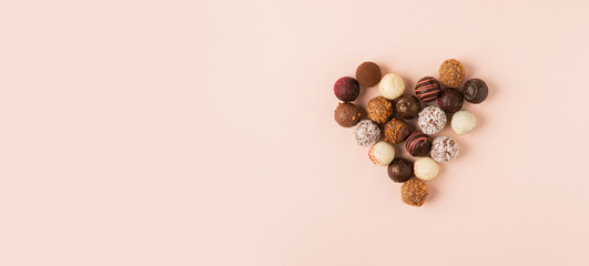 Chocolate truffle candies with different heart filling pastel pink background