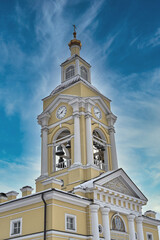 Fototapeta na wymiar Christian church with a bell tower and a clock tower against a blue sky