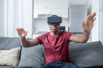 A dark-skinned young man sitting in VR glasses