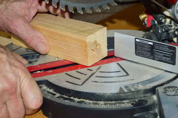 close-up - a man sets the desired angle on a pendulum saw to saw off a wooden baluster - obrazy, fototapety, plakaty