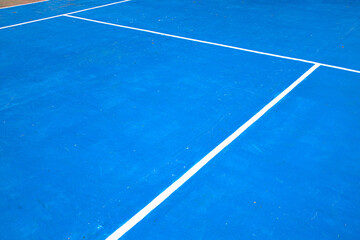 Blue tennis court with white mark. Empty sport field photo. Hard cover surface for lawn tennis. Summer sport activity outdoor. White markup on blue court. Sunny day on tennis court. Sport abstraction