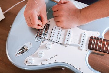 Fototapeta na wymiar Guitar master restringing electric guitar, top view, closeup