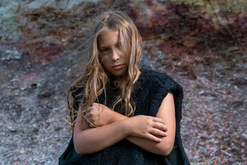 a nine-year-old girl is wrapped in a fur sleeveless jacket and crossed her arms over her chest trying to keep warm