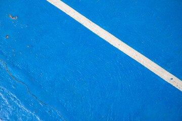 Blue court with white line. Empty sport field photo. Hard cover surface for lawn tennis. Summer sport activity outdoor. White markup on blue court. Sunny day on tennis court. Sport abstraction