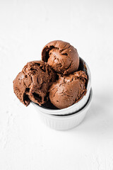 Chocolate ice cream balls in two white bowls, light and bright backdrop