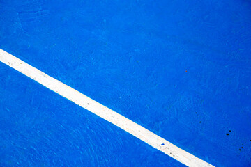 Blue tennis court with white line. Empty sport field photo. Hard cover surface for lawn tennis. Summer sport activity outdoor. White markup on blue court. Sunny day on tennis court. Sport abstraction