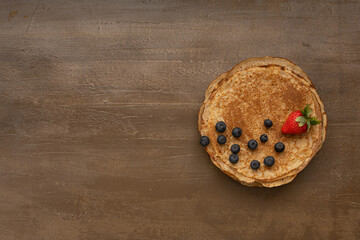Tasty homemade rustic pancake with berries on wooden table. Table top view. Maslenitsa food