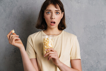 Excited shocked young girl eating popcorn
