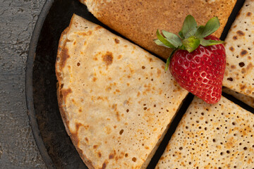 Tasty homemade rustic pancake with berries in a frying pan on wooden table. Table top view. Maslenitsa food