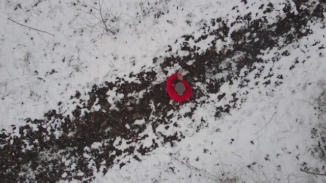 Trail runner on snowy forest track, checking smartwatch fitness stats, aerial