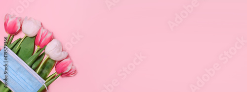 Tulips, medical mask on a pink background.Spring background, Mother's Day, Women's Day, Spring day, Easter background. Copy space.Safe celebration in perdio of the coronavirus outbreak.Banner
