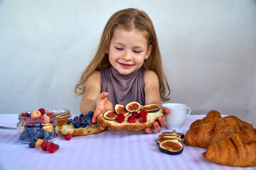 Blonde girl on a white background with a croissant and a cup of milk. Happy child's healthy breakfast. High quality photo