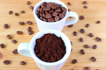 Cup of Ground Coffee with a Cup of Roasted Coffee Beans in the Backdrop
