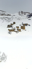a panoramic view from a drone of an ancient fortress in the snow-capped mountains of Ingushetia 