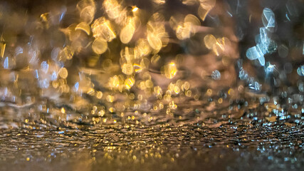 Yellow bokeh effect in night or evening street lighting on car glass in frost. Winter abstract background. A drop of water on the window. The lights are out of focus