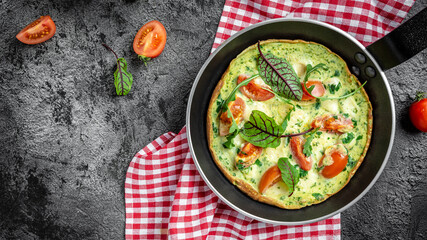 Frying pan with cheese, tomatoes, spinach frittata on dark background. Keto, ketogenic breakfast, lunch. Long banner format, top view