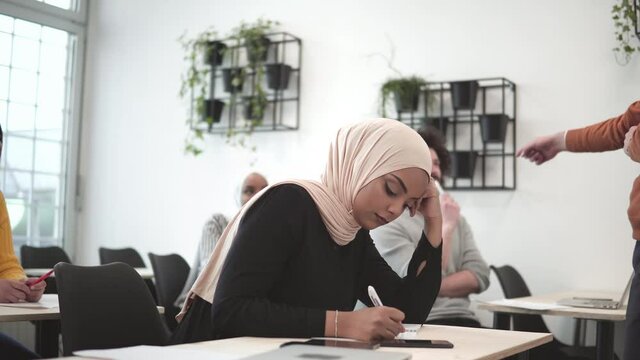 Multiethnical students holding pencil and taking exam in classroom with stress for education test