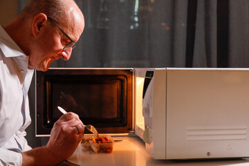 Stockholm, Sweden A man eats alone in front of the microwave.