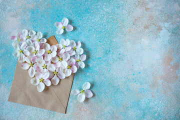 Spring background with envelope and flowers of apple tree in the shape of a heart, colored space...