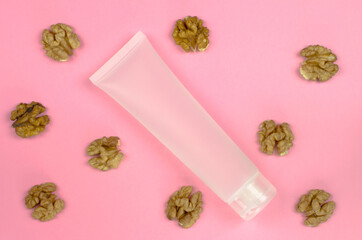White tube for cream and walnuts on a pink background. Organic cosmetics for skin care. Mock-up bottle for branding and label