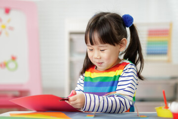 young girl making paper rainbow craft for homeschooling