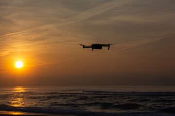 Fototapeta na wymiar Flying drone in the sunset by the sea
