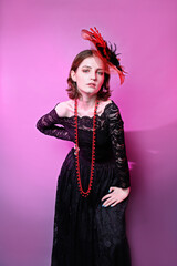 fashionable portrait of young girl in a hat and in black dress. pink background