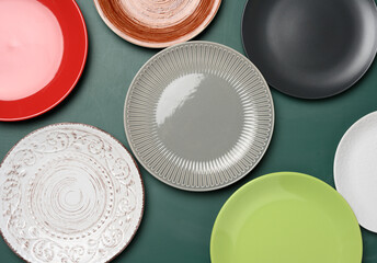 empty round multicolored ceramic plates on green background