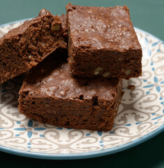 baked square pieces of brownie walnut chocolate cake lie in a round plate