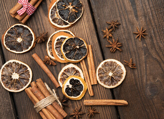 cinnamon sticks and dry orange slices on brown wooden board