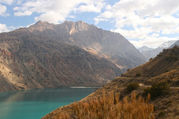 Mirror surface of Lake Iskanderku. The scenic view of Iskanderkul lake and Fann mountains in Tajikistan. Photo with copy space