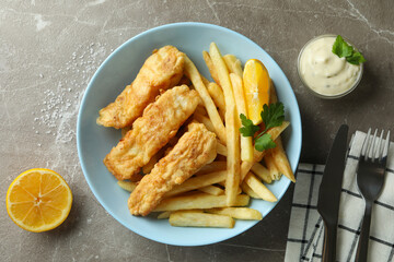 Concept of tasty eating with fried fish and chips on gray textured table