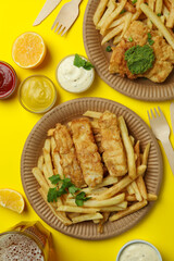 Concept of tasty eating with fried fish and chips on yellow background