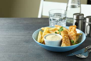 Concept of tasty eating with fried fish and chips on dark textured table