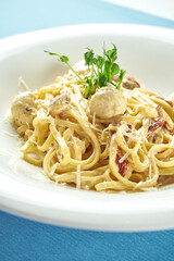 Classic, homemade Italian pasta (spaghetti) in cheese sauce with turkey meatballs and sun-dried tomatoes in a white plate on a blue tablecloth